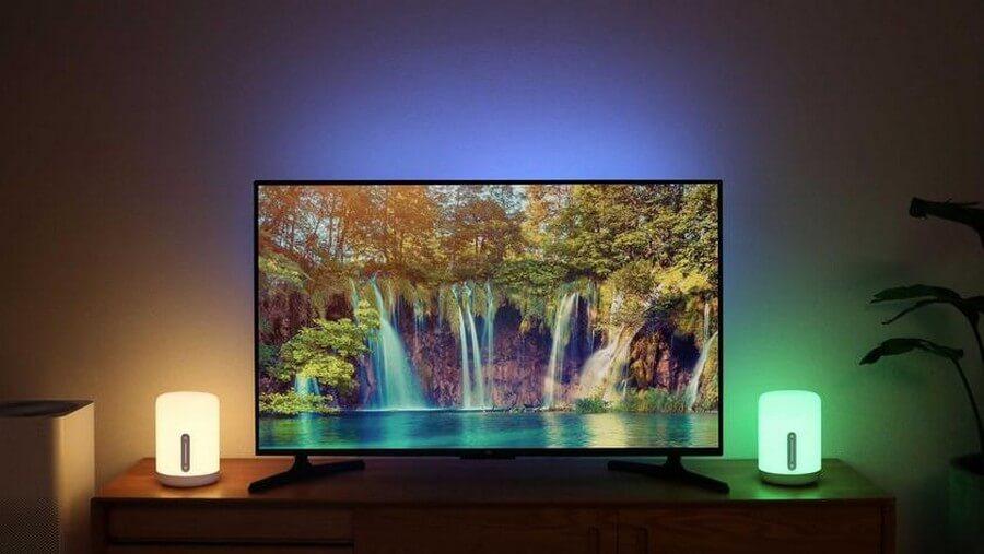 Лампа прикроватная Xiaomi MiJia Bedside Lamp V2 (MJCTD02YL) стоит на полке возле телевизора